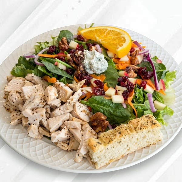 Chicken salad with cranberries, walnuts, blue cheese, orange slice, and focaccia bread.