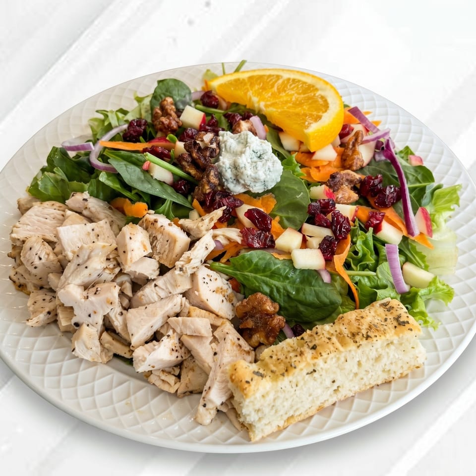 Chicken salad with cranberries, walnuts, blue cheese, orange slice, and focaccia bread.