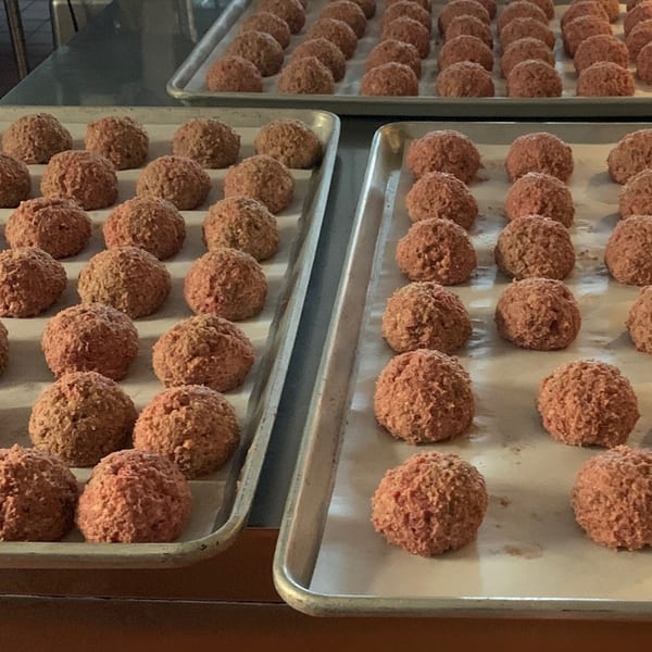 Rows of raw, round meatballs on baking sheets, ready for cooking.
